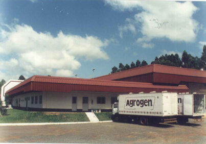 fotografia da sede da Agrogen, com dois caminhões da empresa estacionados a frente e o céu azul